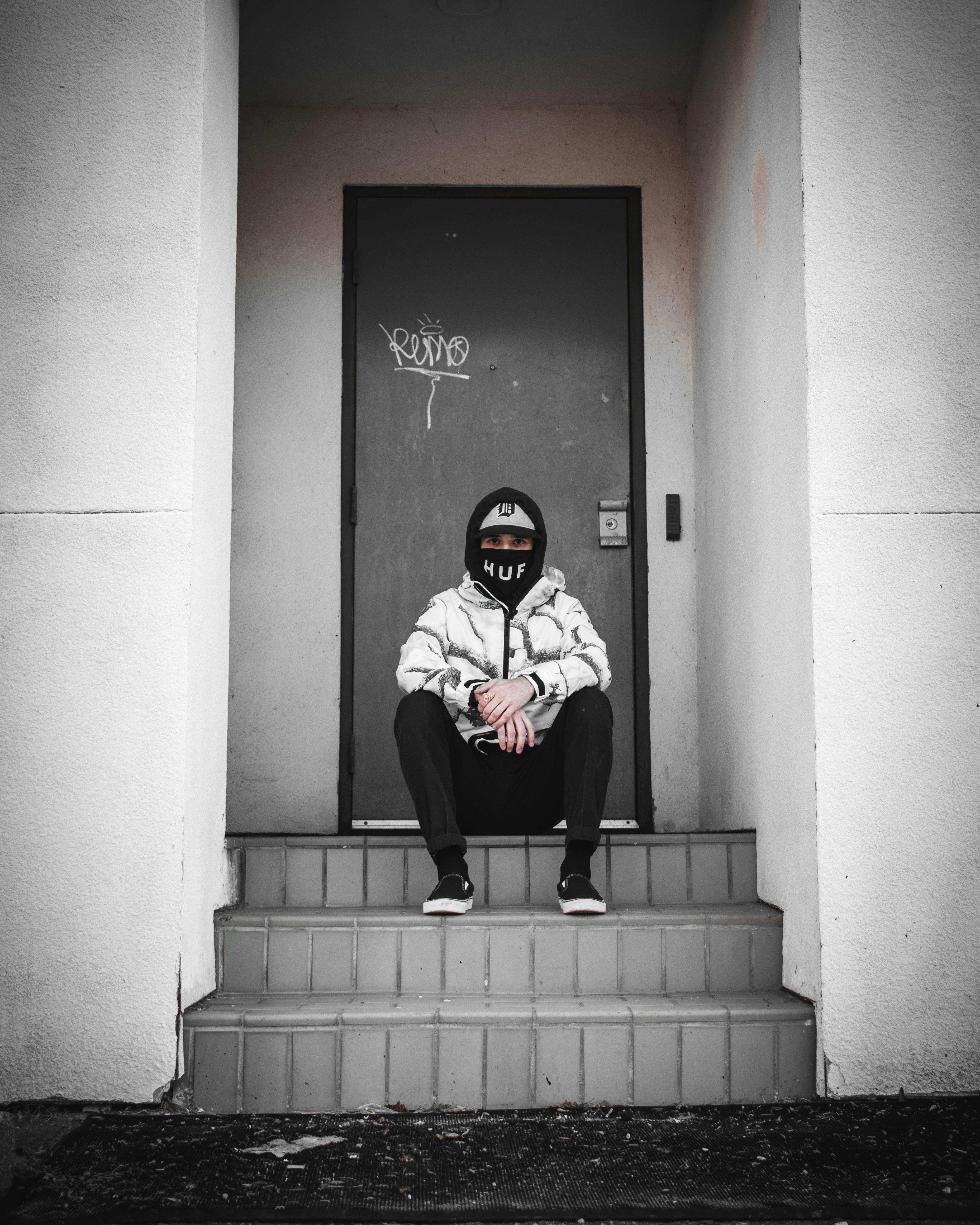 person in black and white mask sitting on stairs